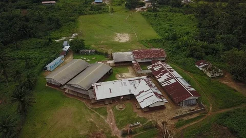 Aerial Circling Around Third World School with US or Liberian Flag on Pole Stock Footage 101622501