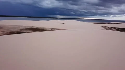 Aerial circular movement around guy alone in dunes of Lencois Maranhenses Stock Footage 168392756