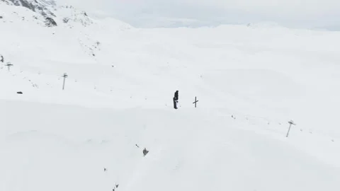 Aerial circular view of snowboarder standing by a summit cross on a mountai.. Stockbeeldmateriaal 342276685
