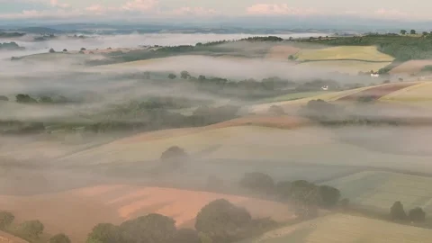 Aerial clip of rolling Devon countryside at dawn on a summer morning, Devon, Stock Footage 283947515