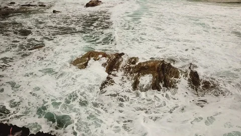 Aerial close approach from above . Waves moving on the rocks. Background Texture Stock Footage 100331143