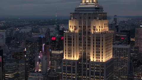 AERIAL CLOSE UP Empire State Building rising above the illuminated New York city Stock Footage