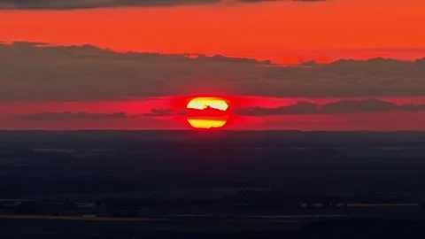Aerial Close-Up of Fiery Setting Sun Split by Cloud Band Over Dark Flatland Stock Footage 334365272