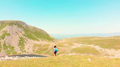 Aerial close up fly over - one Female hiker hike on mountain top in hot summe Stock Footage 201592119