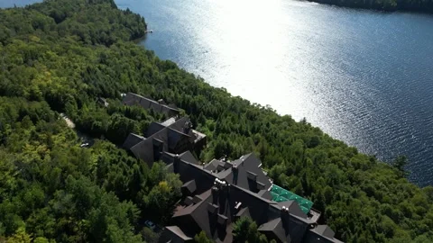 Aerial Close-Up of Lodge Rooftops Beside a Sunlit Lake Vídeos de archivo 338326285