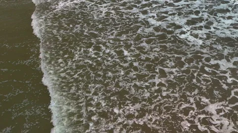 AERIAL Close up of ocean waves rolling onto a beautiful sandy beach at sunrise Stock Footage 286961912