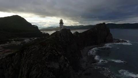 Aerial close old lighthouse on dark high rocks stormy clouds Russia Far East     Stock Footage 99015692