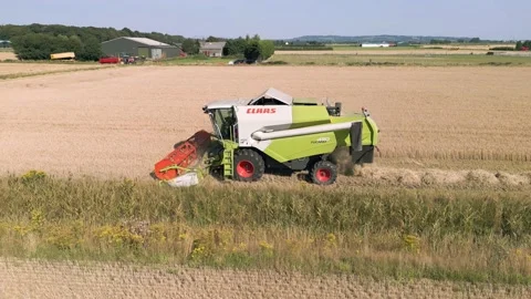 Aerial close up parallel tracking view clip of a combine harvester harvesting Stock-Footage 205330324