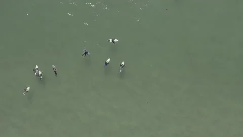 Aerial close up pull away of surfers floating in the ocean off the shore Stock Footage 157133070
