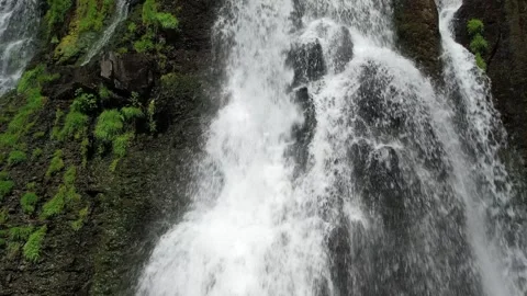 Aerial close-up of Shaki waterfall streams over dark mossy cliff face Stock Footage 342847433
