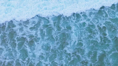 Aerial close-up of turquoise ocean surface with foamy white sea waves Video stock 321977577