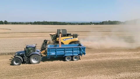 Aerial close up view clip tracking a combine harvester harvesting and unloading Stock Footage 205330814