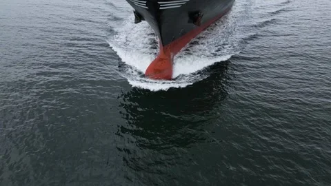 Aerial close-up view of a large cargo ship cutting through the sea, creating Stock Footage 319746631
