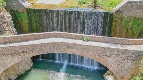 Aerial close up view of an old stone bridge span in front of a cascading wa.. Stock Photos