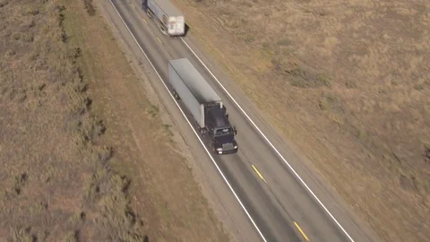 AERIAL CLOSE UP: White semi truck transporter hauling cargo along the highway Stock Footage