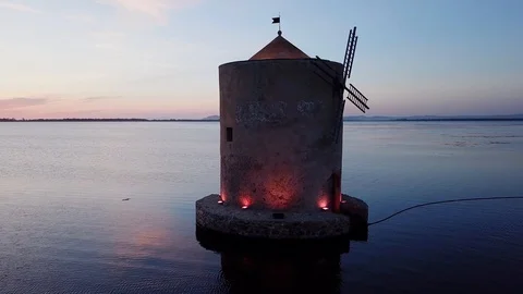 Aerial closeup View A romantic ancient windmill on a sea lagoon at dusk Stock Footage 107847936