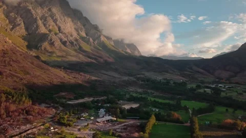 Aerial of cloud-draped mountains over a farmland valley near Franschhoek Stock Footage 346701230