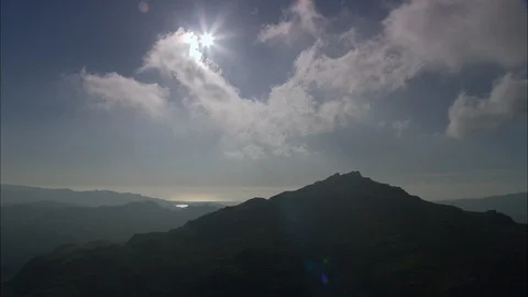 Aerial of clouds above the mountain range at dusk, Harter Fell Back Lit With Sun Stock Footage 108587077