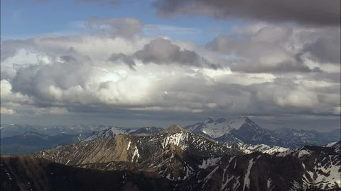 Aerial of clouds above snow-capped mountain ranges, Flathead Range Stock Footage 109455249
