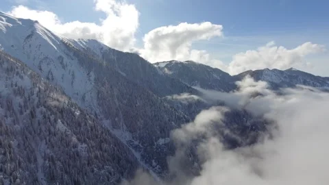 Aerial clouds drifting above snowy mountain ranges and deep - Grove and Texture Stock Footage 339449910