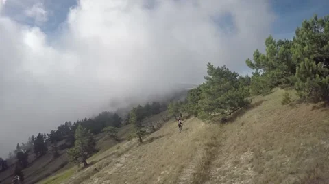 Aerial of clouds float over the mountains, biker, sky, forest, trees, dry grass Stock Footage 57260150