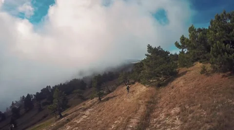 Aerial of clouds float over the mountains, biker, sky, forest, trees, dry grass Stock Footage 57260182