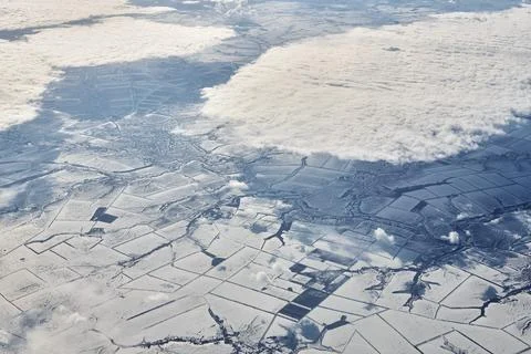 Aerial cloudscape view over clouds top to snow covered rivers, roads, cities  Stock Photos