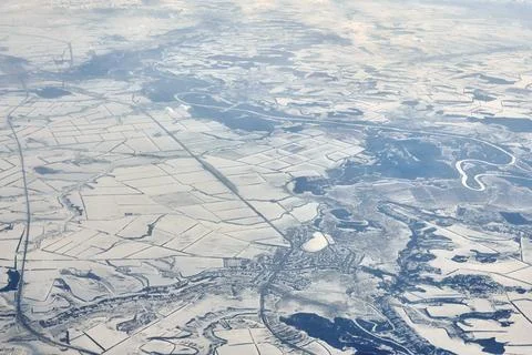 Aerial cloudscape view over clouds top to snow covered rivers, roads, citie.. Stock Photos