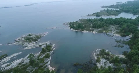 Aerial On Cloudy Lake Over Smooth Glacier Rock And Pine Northern Lake Shoreline Stock Footage 188480153