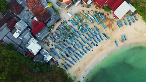 Aerial coastal panorama shows rows of blue fishing boats, village buildings.. Stock Footage 341545337