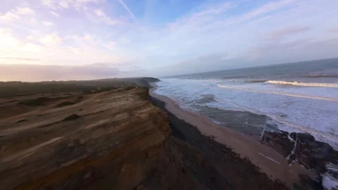 Aerial coastal scene with cliffs, beach, and gentle waves Stock Footage 344676927