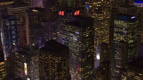 AERIAL: Colorful brightly illuminated Times Square under tall glassy skyscrapers Stock Footage
