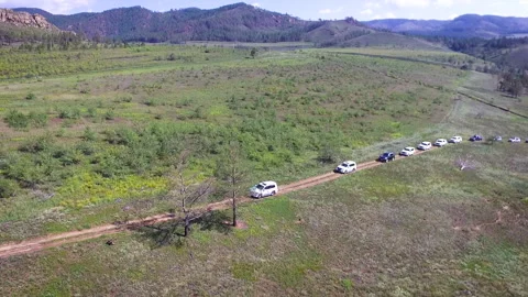 Aerial of a column of SUVs on a mountain highway. Rear view of the river and Stock Footage 154267722