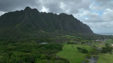 Aerial Crab Left Past Fluted Green Volcanic Ridge Above Grass Park And Forest Vídeo Stock 342652178