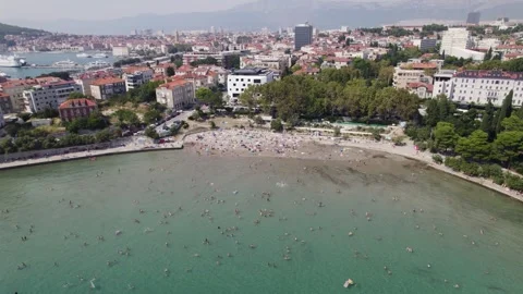 Aerial: Croatia, Bacvice Beach, Split, with swimmers and cityscape backdrop Stock Footage 252359698