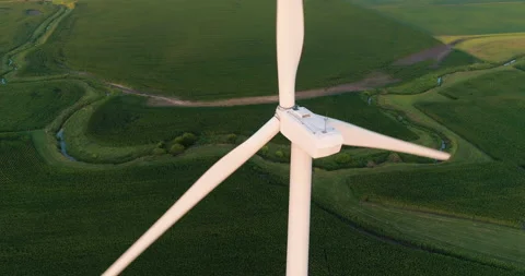 Aerial CU view of Wind Turbine tower and green fields with sunset light Stock Footage