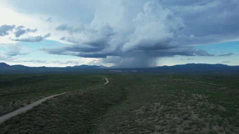 Aerial of a curvy road leading to a dramatic monsoon thunderstorm Stock Footage 202320488