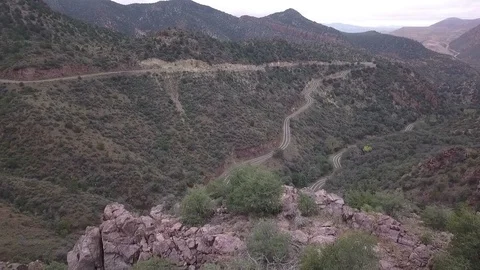 Aerial of a curvy road with switchbacks in a rugged desert valley Stock Footage 96994924