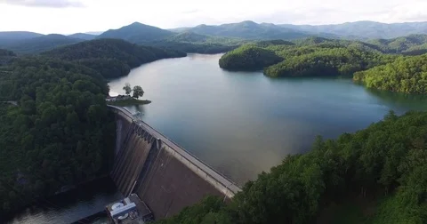 Aerial of dam surrounded with green forest and mountains Stock Footage
