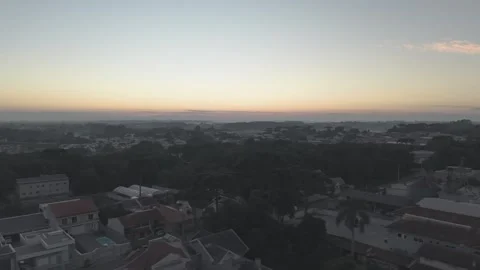 Aerial dawn lateral movement over suburban city toward sunrise horizon Vídeos de archivo 333909557