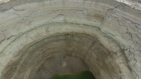 Aerial a deep sinkhole depression on a flat plain landscape across barren ground Stock Footage 339560197