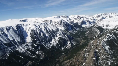 Aerial of deep valley and switchback road under mountain ridge covered with snow 스톡 동영상 124226016