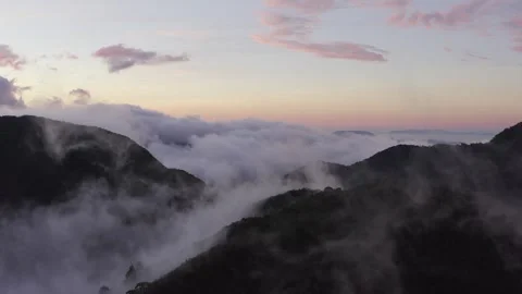 Aerial descending through wispy clouds towards mountain forest landscape and 스톡 동영상 284248528