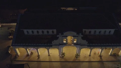 Aerial descends while tilting up to reveal market in Mompox, Colombia at night Видео 108580104