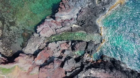 Aerial descent tracking unique textures of coastal red black rocks 4K Stock Footage 336230598