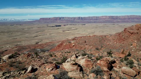Aerial-Desert plain and distant plateau-Pull back over rocky hill top Stock Footage 238769563