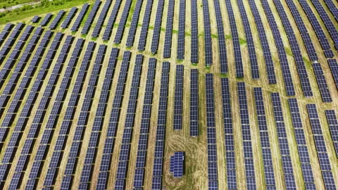 Aerial diagonal solar mosaic with repeating panel rows, angled tracks, tiny Stock Footage 337947229