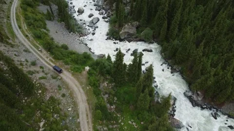  Aerial Diagonal View of Black SUV Driving by Rushing Mountain River Video stock 331991221