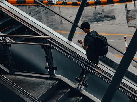 Aerial Diagonal View of Man with Backpack Descending Station Escalator Foto stock