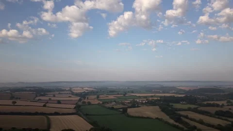Aerial Dolly Forward over Patchwork Fields Beneath Clouds Stock Footage 347974949